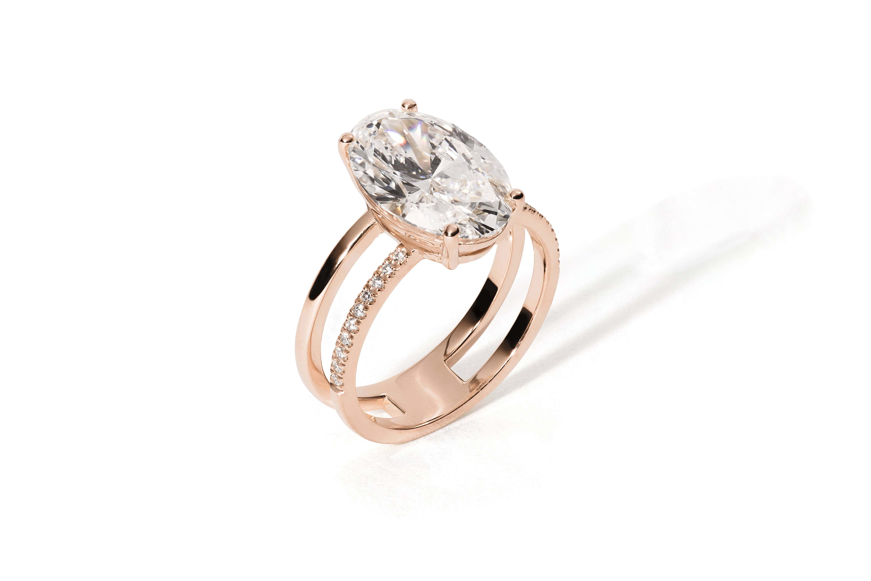 Das HERA ROSÉGOLD von Atelier Sofia verfügt über einen Ring aus 18 Karat Roségold mit einem schillernden, im Ovalschliff gefertigten, im Labor gezüchteten Diamanten und kleinen Diamanten auf einer Seite, die sich wunderschön vor einem schlichten weißen Hintergrund abheben.