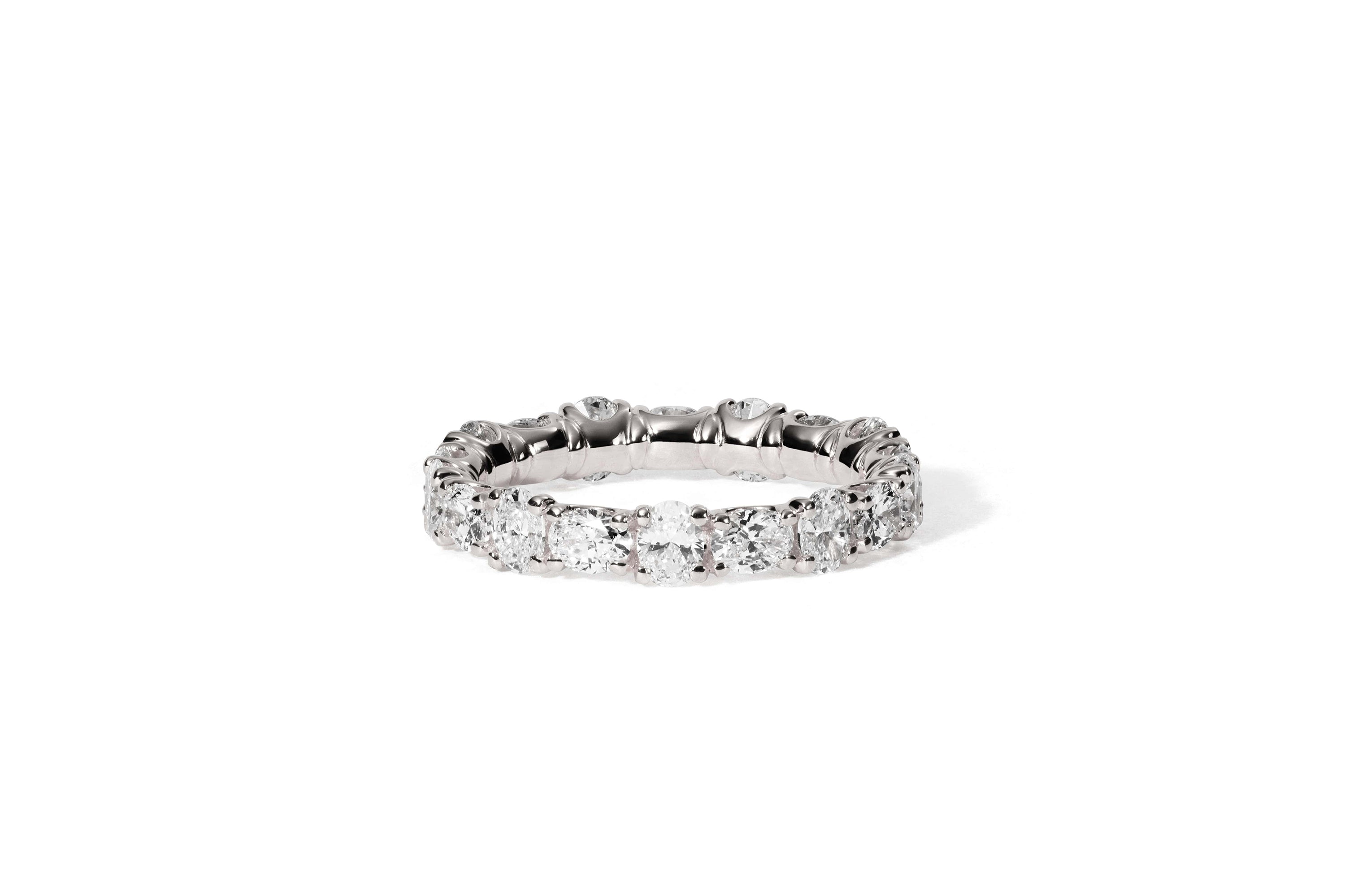 Der KALLIOPI WEIßGOLD Eternity-Ring von Atelier Sofia zeigt einen nahtlosen Kreis aus Diamanten im Rundschliff, die elegant vor einem schlichten weißen Hintergrund angeordnet sind.